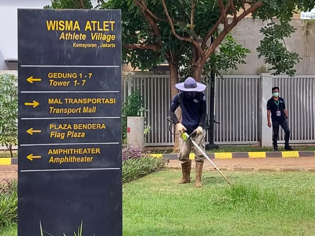 Petugas kebersihan tengah memangkas rumput di halaman Rumah Sakit Darurat COVID-19 Wisma Atlet Kemayoran, Jakarta Pusat, Selasa (12-7-2022). (ANTARA/Fianda Sjofjan Rassat)