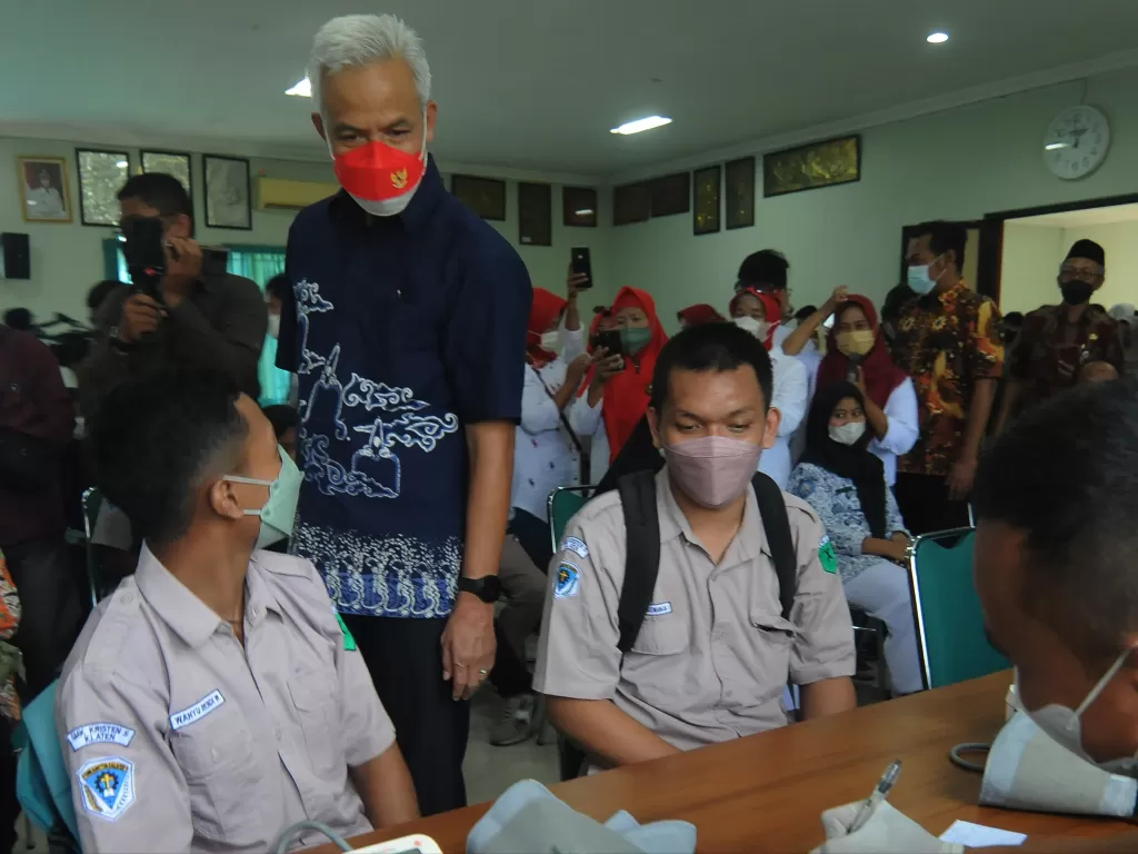 Gubernur Jawa Tengah Ganjar Pranowo (tengah) berbincang dengan siswa saat kegiatan vaksinasi COVID-19. (ANTARA FOTO/Aloysius Jarot Nugroho)