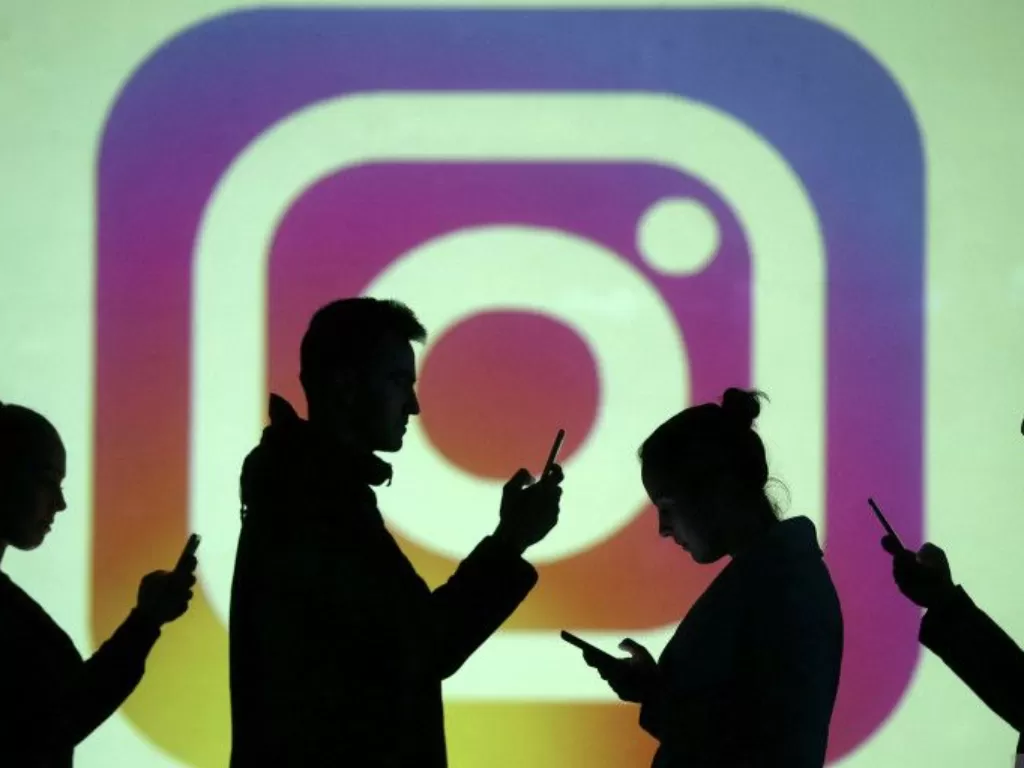 Ilustrasi - Siluet pengguna ponsel terlihat di sebelah proyeksi layar logo Instagram. (REUTERS/Dado Ruvic)