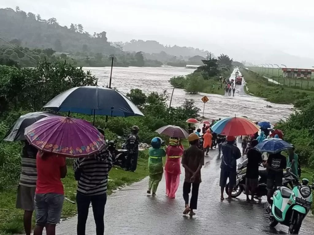 Warga menyaksikan air Sungai Sikula yang meluap dan melewati ruas di dekat Bandara Internasional Pattimura Ambon, Maluku, Selasa (26/7/022). (ANTARA/Jimmy Ayal)