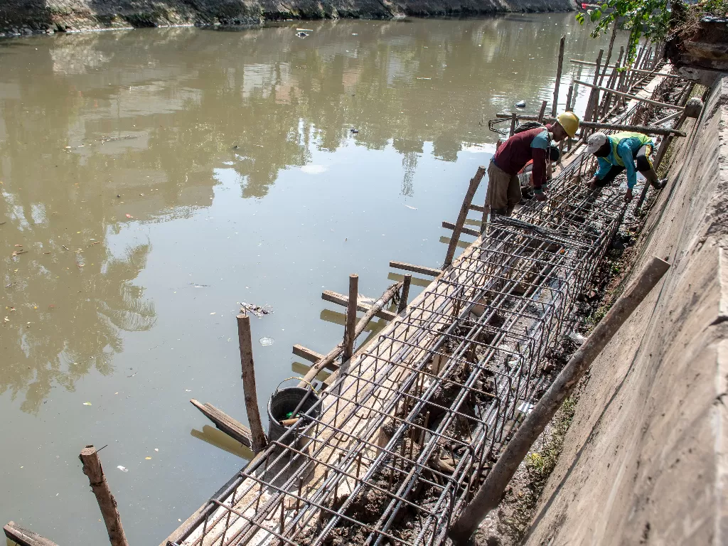 Pekerja menyelesaikan pembangunan turap anak sungai Ciliwung di Jakarta. (ANTARA/Muhammad Adimaja)