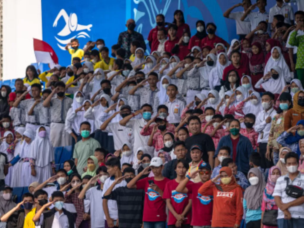 Sejumlah warga dan pelajar memberikan penghormatan kepada bendera Indonesia usai penyerahan medali emas pertandingan para-renang ASEAN Para Games 2022. (ANTARA FOTO/Aji Styawan)