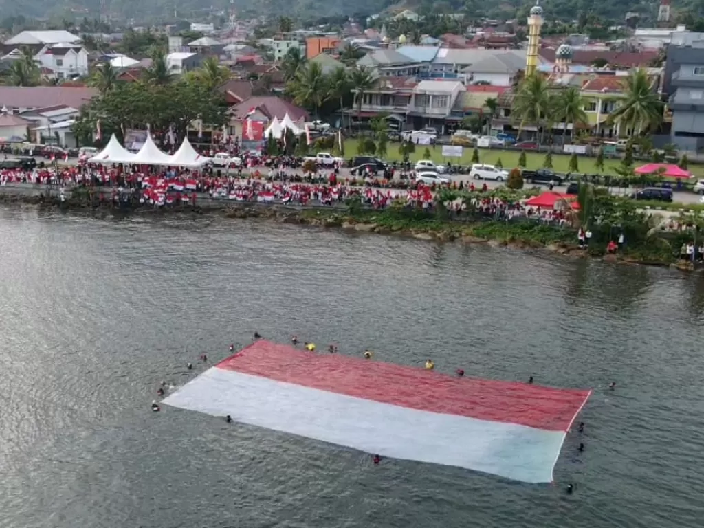 Pengibaran bendera merah putih raksasa berukuran 21 x 11 meter yang juga dirangkaikan dengan jalan santai yang dihadiri ratusan pejabat pemerintah Sulbar, Sabtu (13/8/2022). (Istimewa)