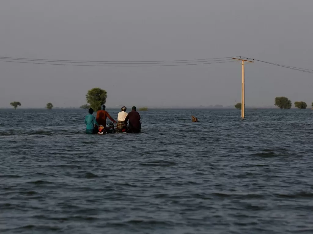 Sejumlah warga tengah coba menerjang banjir yang melanda bagian selatan Pakistan. (REUTERS/Akhtar Soomro)