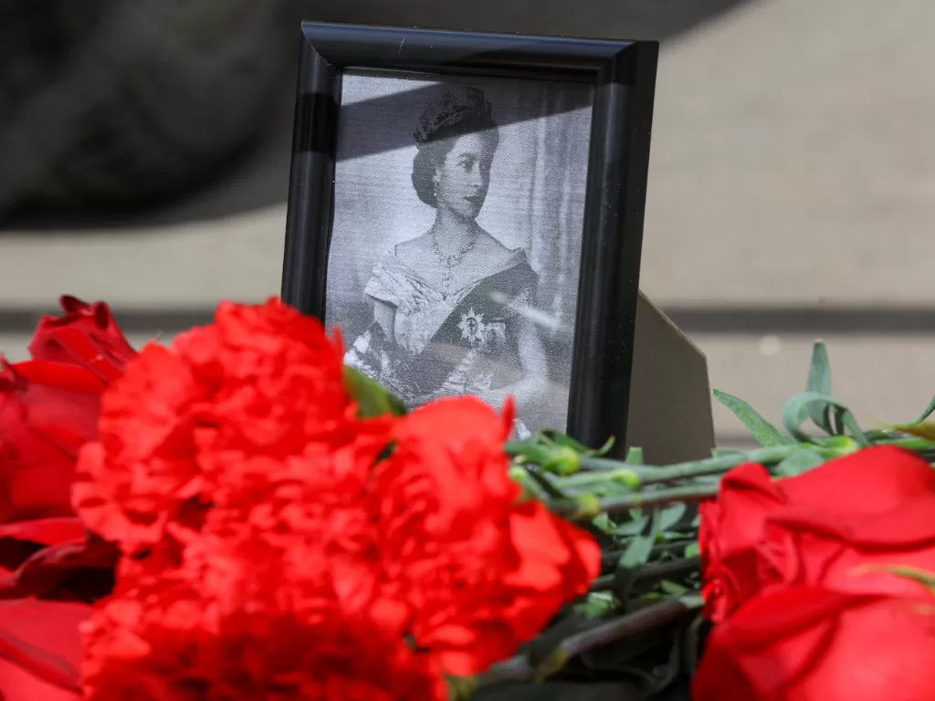 Pemandangan menunjukkan potret dan bunga ditempatkan untuk memberi penghormatan kepada Ratu Elizabeth atas kematiannya. (REUTERS/Evgenia Novozhenina)