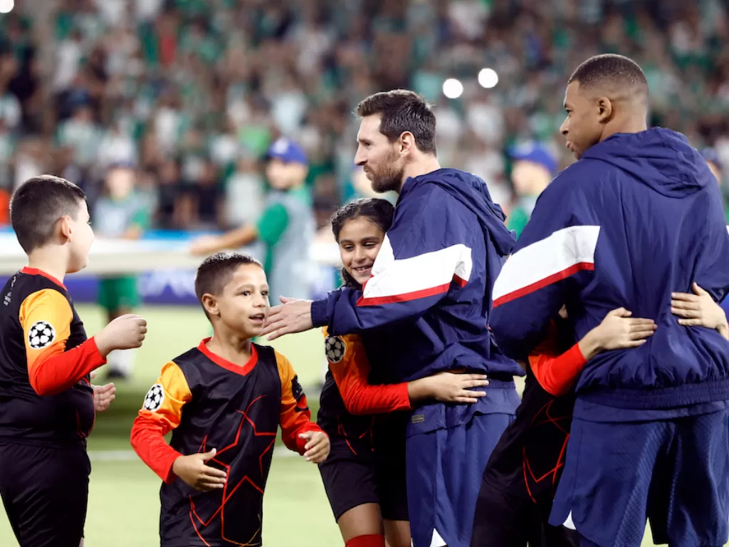 Lionel Messi dan Kylian Mbappe memeluk bocah maskot (REUTERS/Nir Elias)