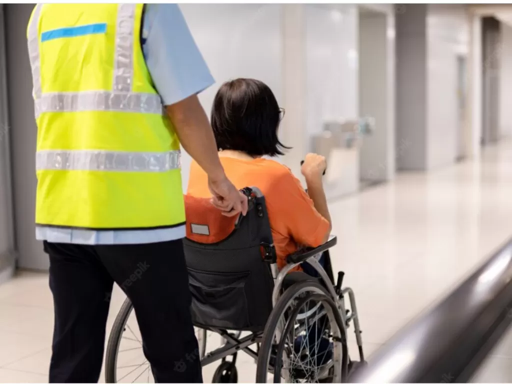 Ilustrasi petugas bandara membantu pengguna kursi roda untuk menaiki pesawatnya. (Freepik/bignai).