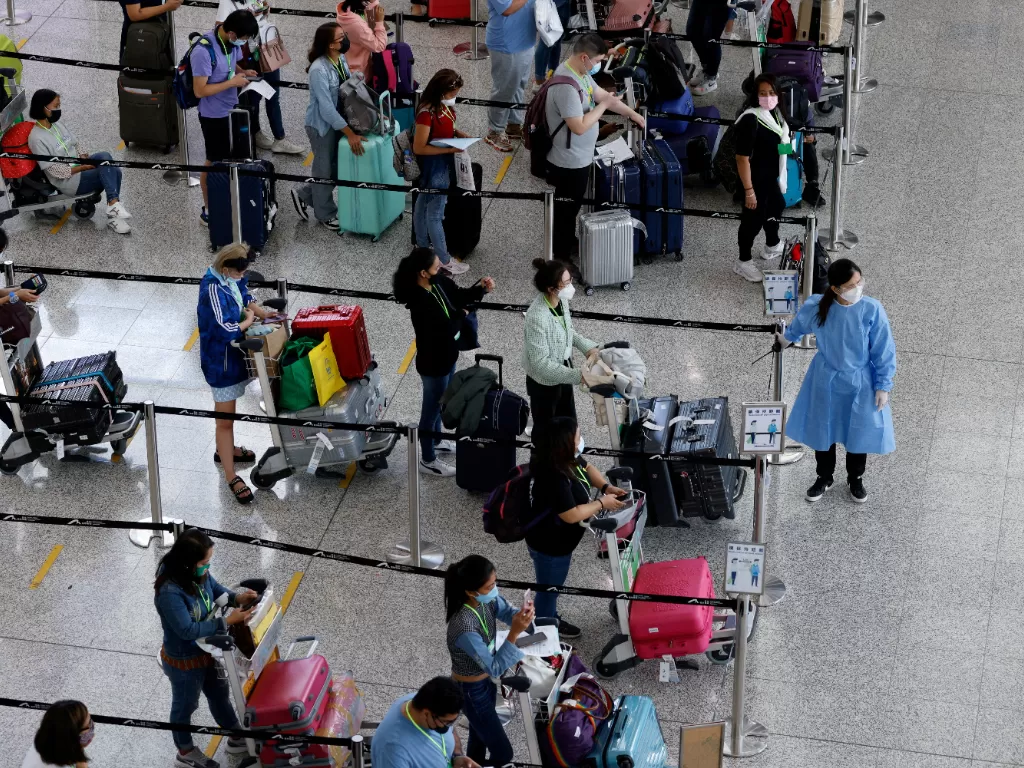 Wisatawan mengantre untuk bus antar-jemput ke hotel karantina di Bandara Internasional Hong Kong. (REUTERS/Tyrone Siu)