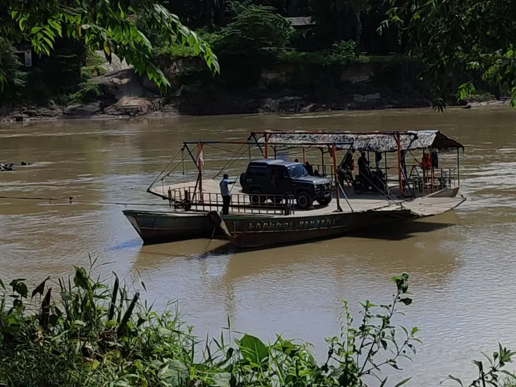 Warga di Langkat menyebrang menggunakan perahu getek. (Z Creators/Muhammad Hijrah)
