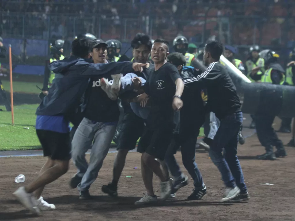 Sejumlah penonton membawa rekannya yang pingsan akibat sesak nafas terkena gas air mata di Stadion Kanjuruhan, Malang, Sabtu (1/10/2022) (ANTARA/Ari Bowo Sucipto)