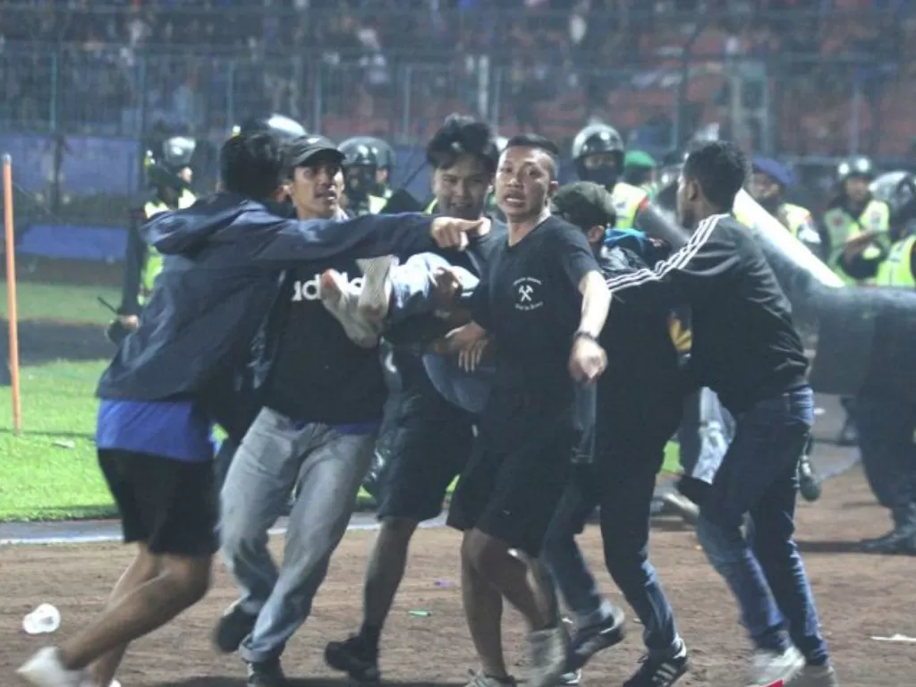 Sejumlah penonton membawa rekannya yang pingsan akibat sesak nafas terkena gas air mata yang ditembakkan aparat keamanan saat kericuhan usai pertandingan sepak bola BRI Liga 1 antara Arema melawan Persebaya di Stadion Kanjuruhan, Malang. (ANTARA/Ari Bowo 