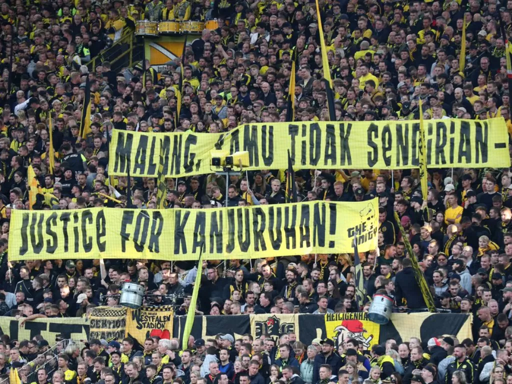 Suporter Borussia Dortmund bentangkan spanduk bernada empati untuk tragedi Kanjuruhan di laga Der Klassiker, Sabtu (8/10/2022). (Twitter)