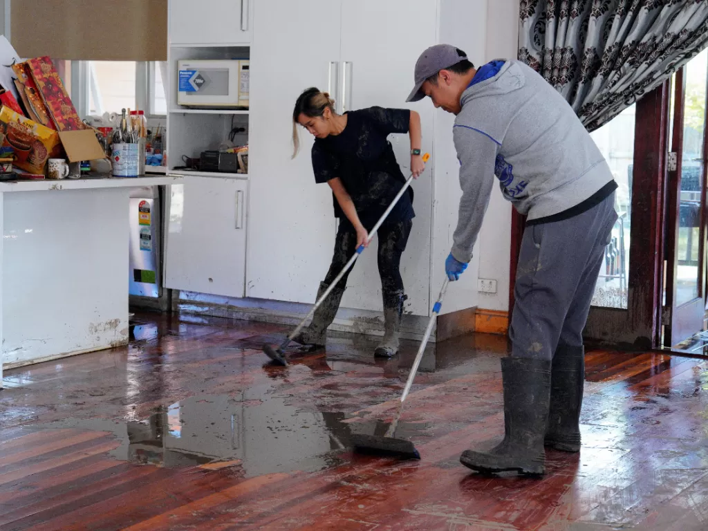 Warga Australia membersihkan rumah yang terkena banjir. (REUTERS/Sandra Sanders)