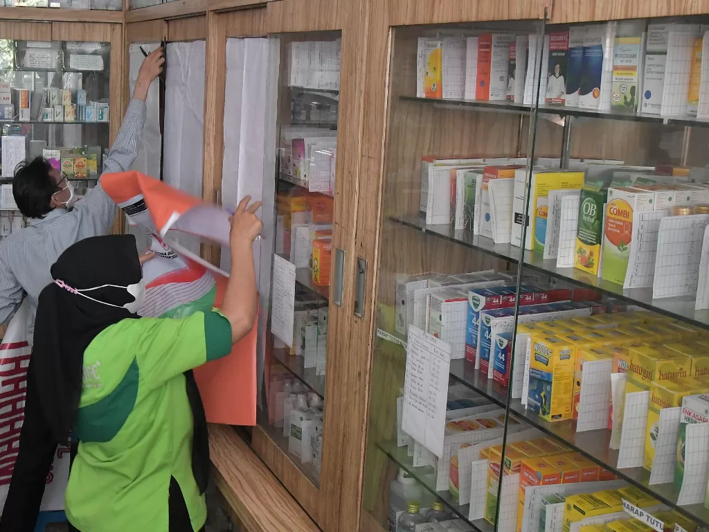 Sejumlah pedagang menutup dengan kain lemari yang menyimpan obat sirup di apotek usai inspeksi mendadak (sidak) di Bekasi, Jawa Barat, Senin (24/10/2022). (ANTARA/Fakhri Hermansyah)