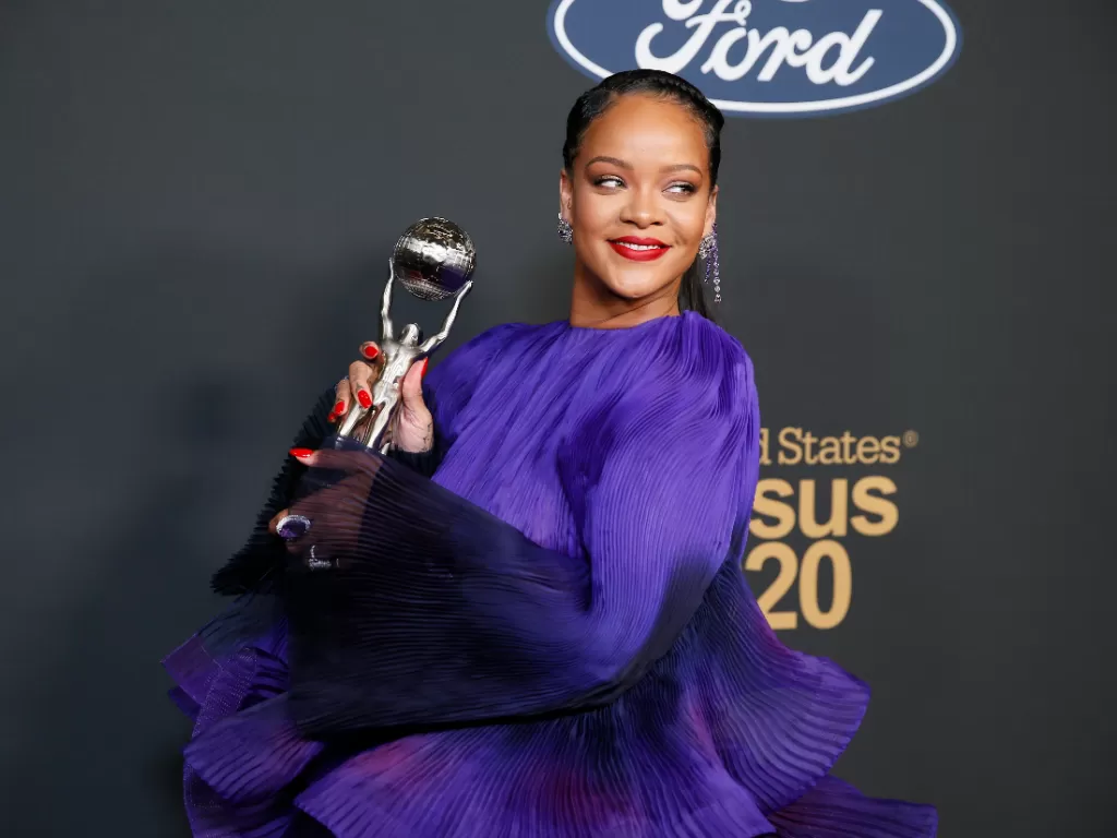 Rihanna berpose di belakang panggung dengan penghargaan Presidennya. (REUTERS)