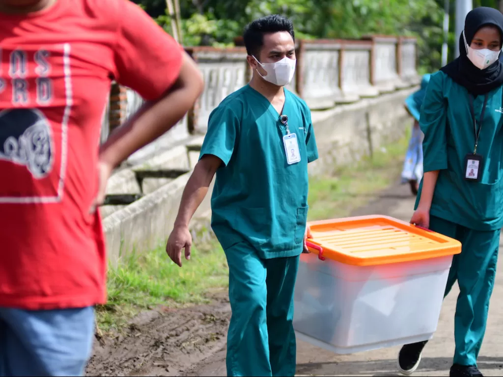 Dua anggota tim dari Perhimpunan Dokter Forensik Indonesia (PDFI) mengangkat kotak peralatan usai melakukan ekshumasi jenazah dua korban Tragedi Kanjuruhan (ANTARA FOTO/Purnomo)