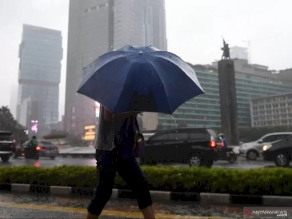 Warga menggunakan payung untuk menghindari hujan saat melewati kawasan Bundaran Hotel Indonesia, Jakarta. (ANTARA FOTO/Akbar Nugroho Gumay)