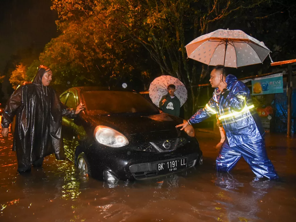 Petugas berusaha mengevakuasi mobil yang mogok akibat tergenang banjir di Jalan Perjuangan, Medan, Sumatera Utara, Jumat (18/11/2022). (ANTARA/Fransisco Carolio)