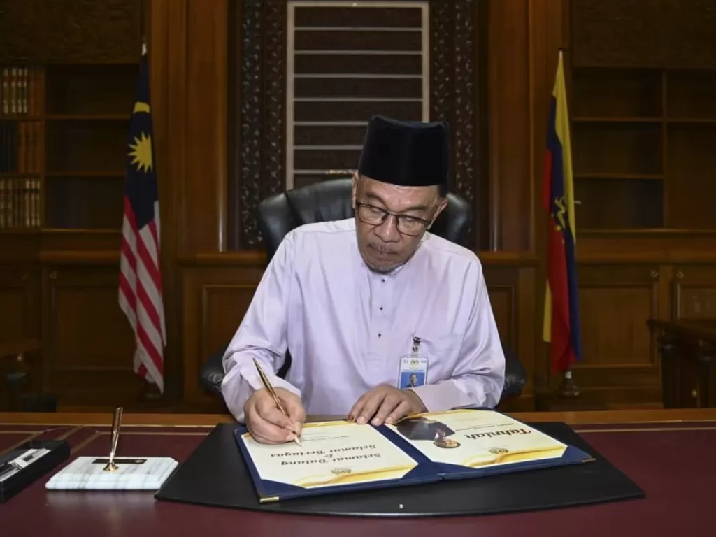 Anwar Ibrahim menandatangani dokumen usai bertugas sebagai Perdana Menteri Malaysia. (Malaysia Information Ministry)