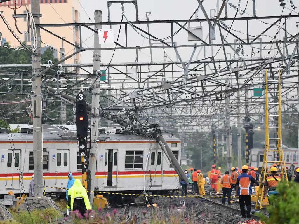 Sejumlah petugas berupaya mengevakuasi rangkaian kereta rel listrik (KRL) Commuterline KA 5144C yang anjlok dan tertimpa tiang listrik di perlintasan Stasiun Kampung Bandan, Jakarta. (ANTARA/Aditya Pradana Putra)