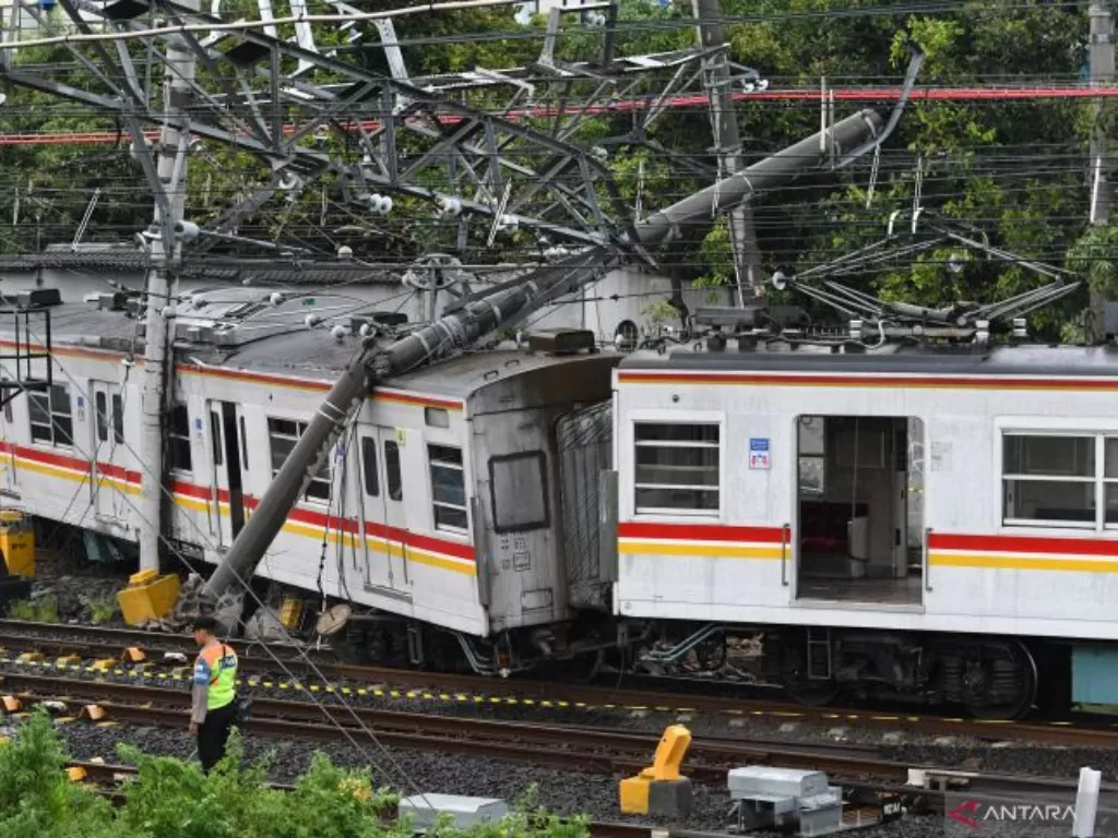 Petugas keamanan berjaga di dekat rangkaian kereta rel listrik (KRL) Commuterline KA 5144C yang anjlok dan tertimpa tiang listrik di perlintasan Stasiun Kampung Bandan, Jakarta, Sabtu (26/11/2022). Akibat proses evakuasi rangkaian KRL tersebut, perjalanan
