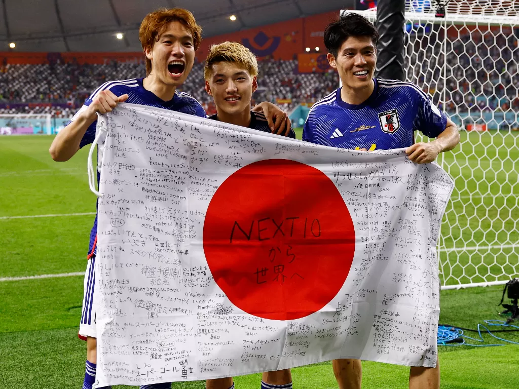 Pemain timnas Jepang membentangkan bendera negaranya di lapangan usai laga Piala Dunia 2022. (REUTERS/Susana Vera)