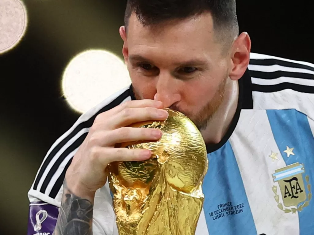 Lionel Messi mencium trofi Piala Dunia usai membawa Argentina mengalahkan Prancis di partai final. (REUTERS/Carl Recine)