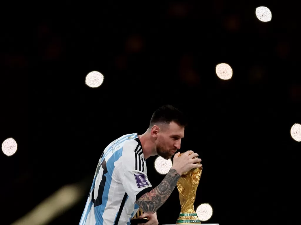 Lionel Messi mencium trofi Piala Dunia (Reuters/Lee Smith)
