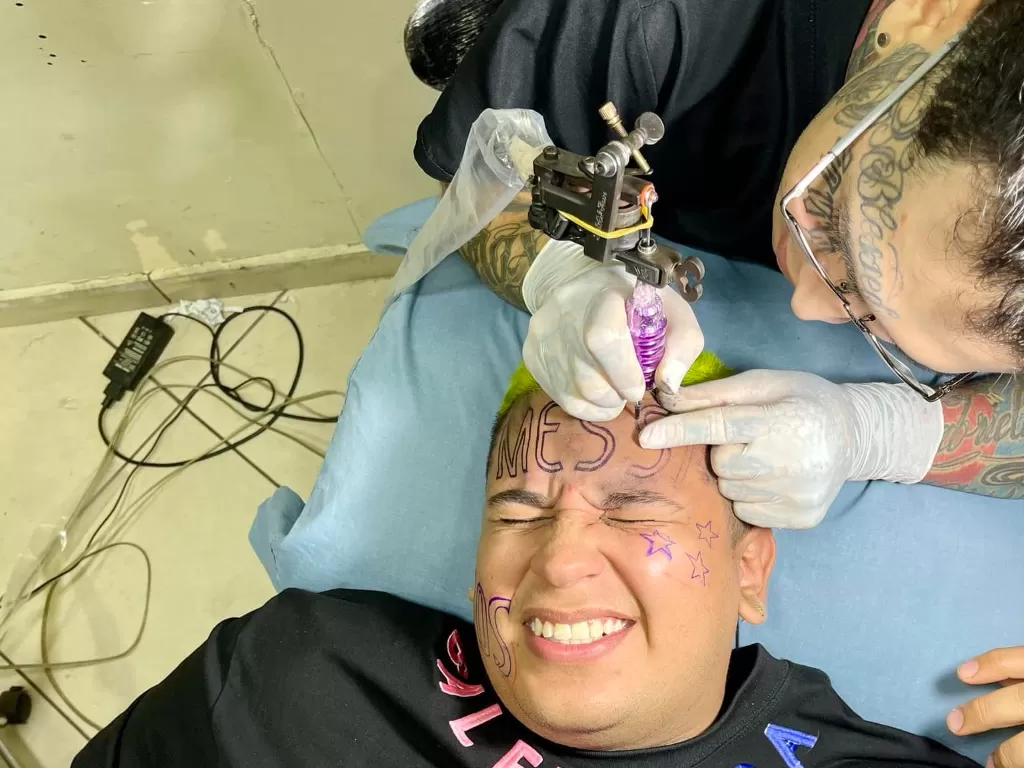 Seorang pria membuat tato bertuliskan MESSI di wajahnya (Facebook/Mike Jambs)