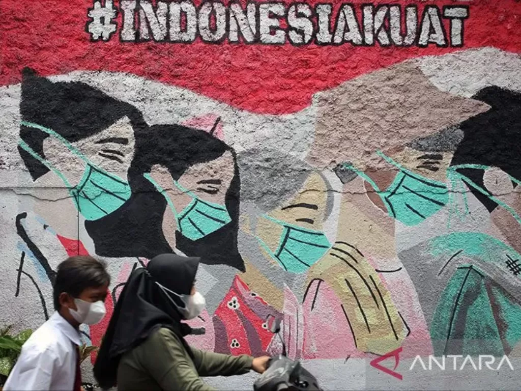 Pengendara motor melintas di depan mural edukasi pemakaian masker untuk mencegah penularan COVID-19 di Tangerang Selatan, Banten. (ANTARA FOTO/MUHAMMAD IQBAL)