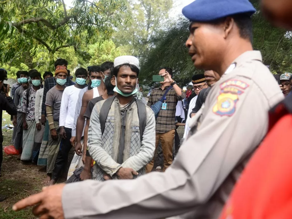 Personel Polda Aceh memberikan pengawalan pemindahan sejumlah imigran etnis Rohingya setelah terdampar di pantai Desa Ladong, Kabupaten Aceh Besar, Aceh. (ANTARA FOTO/Ampelsa)