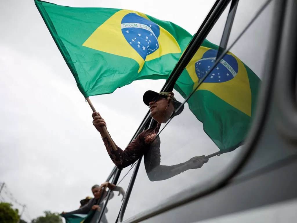 Bendera Brasil dikibarkan oleh seorang warga (REUTERS/Amanda Perobelli)