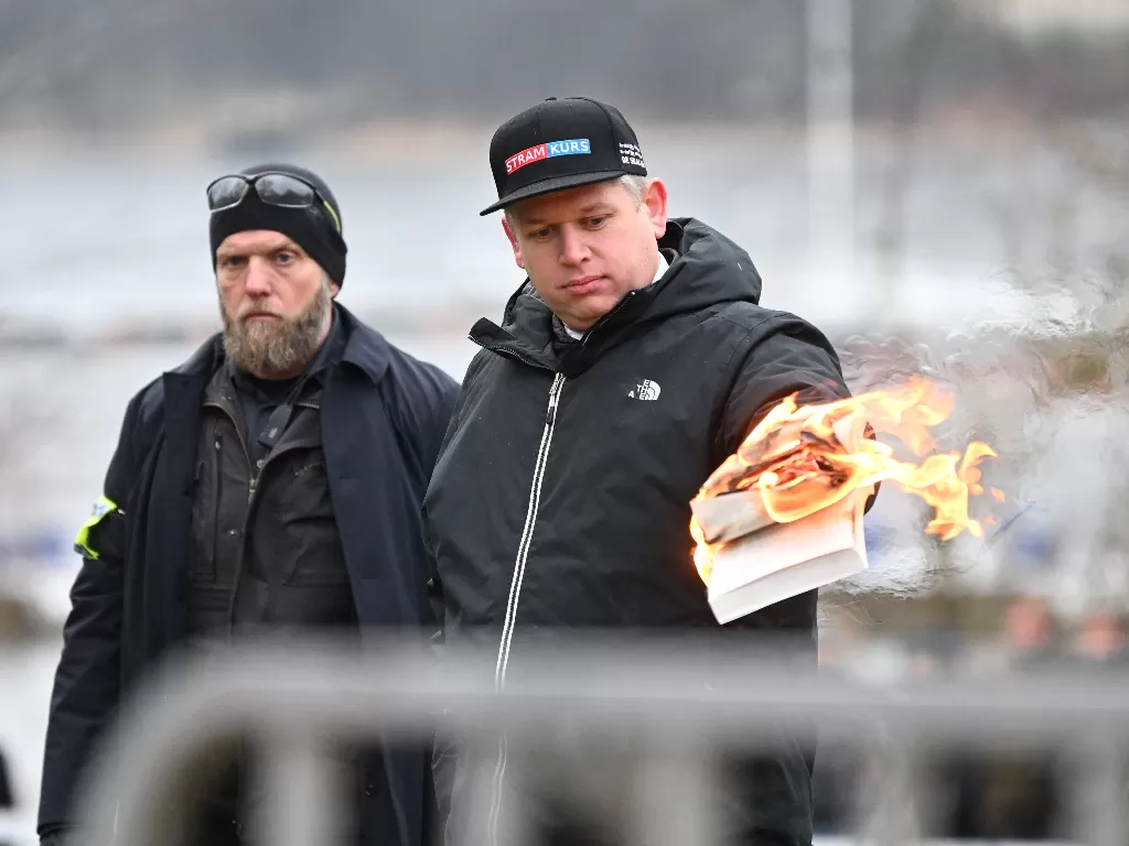 Aksi politisi sayap kanan Denmark Stram Kurs, Rasmus Paludan membakar salinan Al Quran di luar Kedutaan Besar Turki di Stockholm pada Sabtu (21/1) (Fredrik Sandberg/TT News Agency/via REUTERS)
