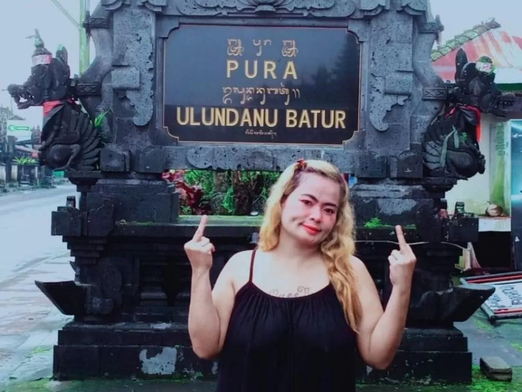 Wanita yang berpose jari tengah di depan pura Bali. (Facebook/Faras Sayidi)