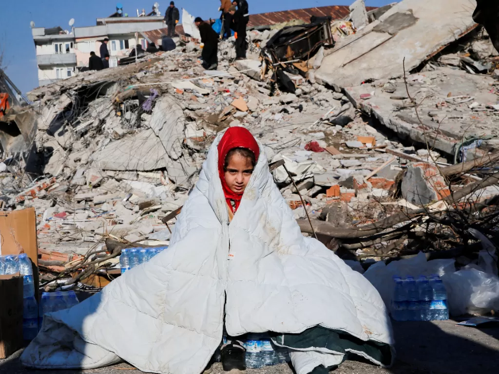 Seorang anak perempuan di antara reruntuhan bangunan yang runtuh usai gempa M 7,8 mengguncang Turki. (REUTERS/Dilara Senkaya)