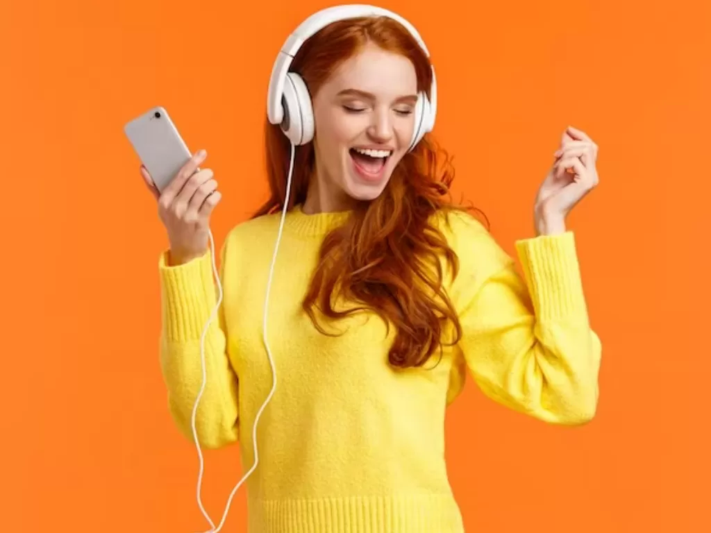 Ilustrasi seorang wanita mendengarkan lagu dengan headphone. (FREEPIK/@benzoix)