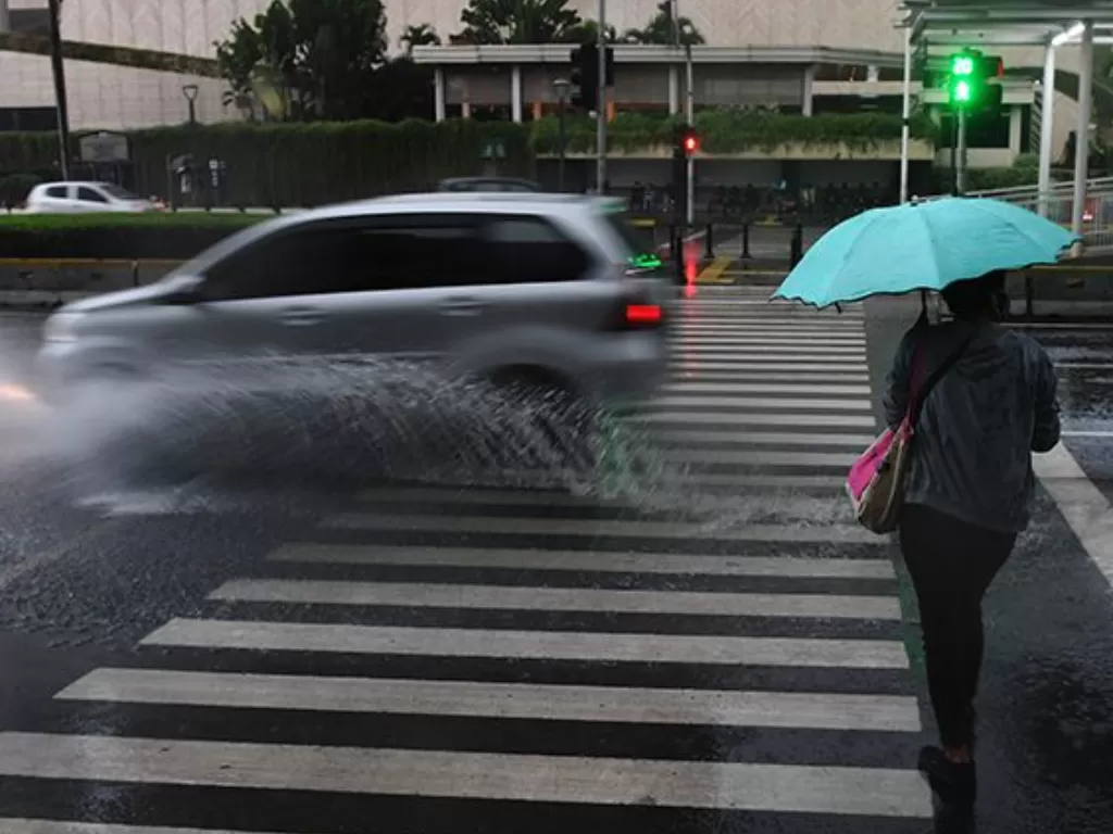 Ilustrasi warga mengunakan payung sedang menyeberangi jalan. (ANTARA FOTO/Akbar Nugroho Gumay)