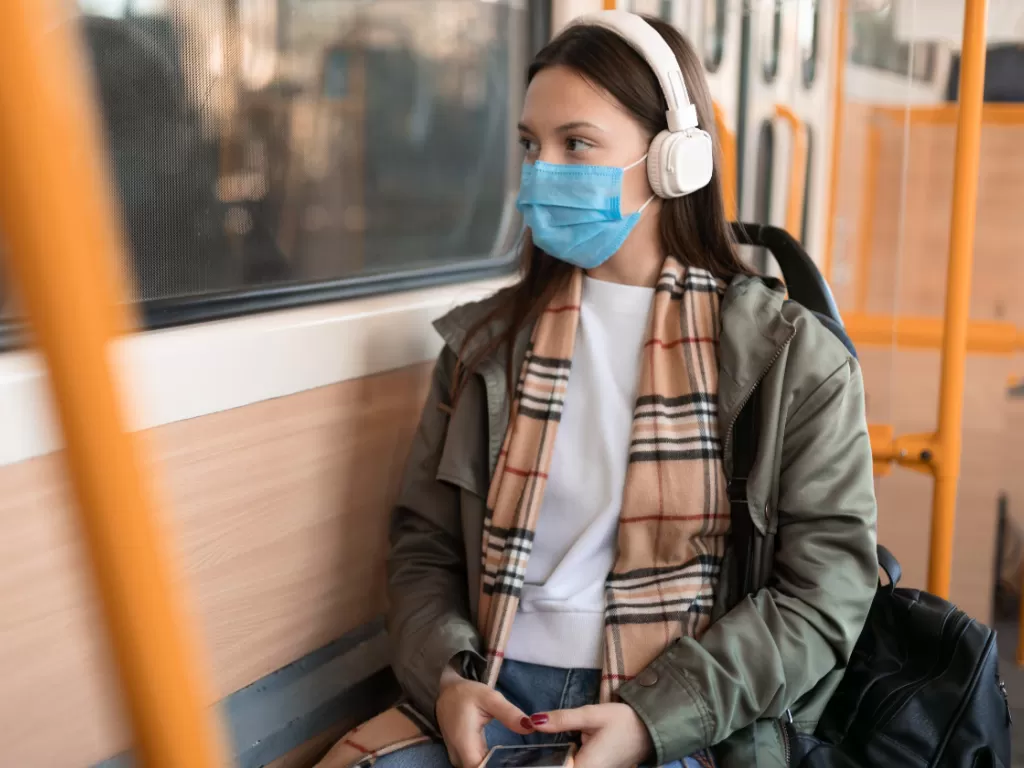 Ilustrasi wanita pakai masker di transportasi umum. (Freepik)