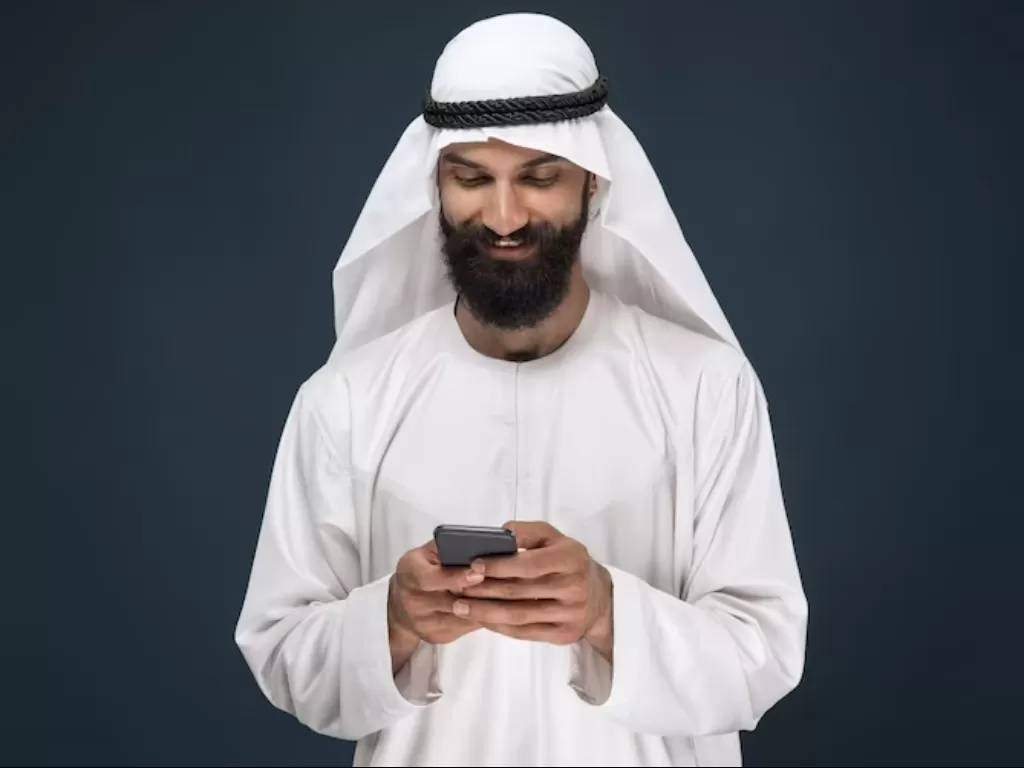 Seorang pria muslim mengoperasikan smartphone. (FREEPIK/@master1305)