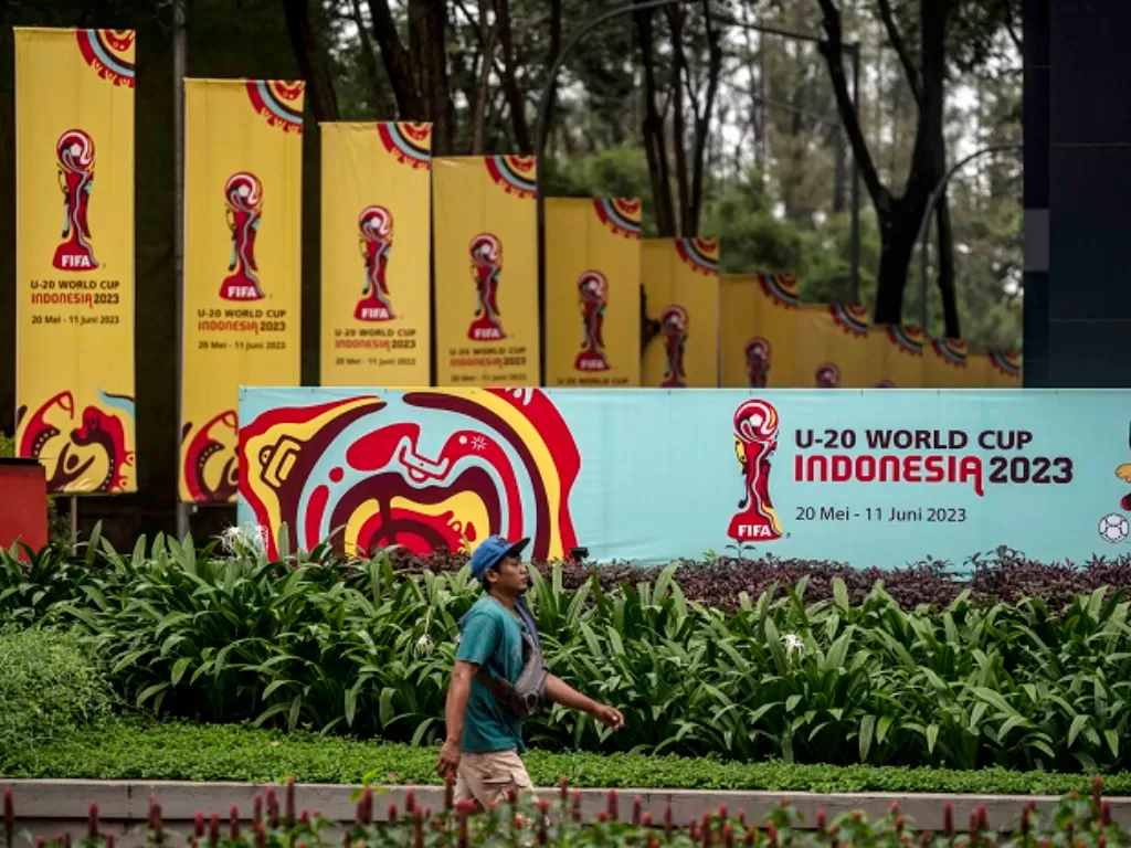 Warga berjalan di dekat papan promosi Piala Dunia U-20 Indonesia 2023 di kawasan GBK Arena. (ANTARA FOTO/Aprillio Akbar)