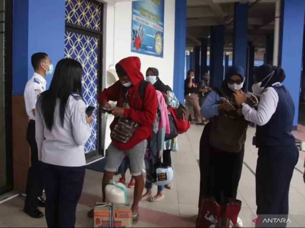 Petugas memeriksa sertifikat vaksin COVID-19 dan membagikan masker bagi penumpang di Terminal Tirtonadi Solo, Jawa Tengah, Rabu (13/4/2022). (ANTARAFOTO/Maulana Surya)