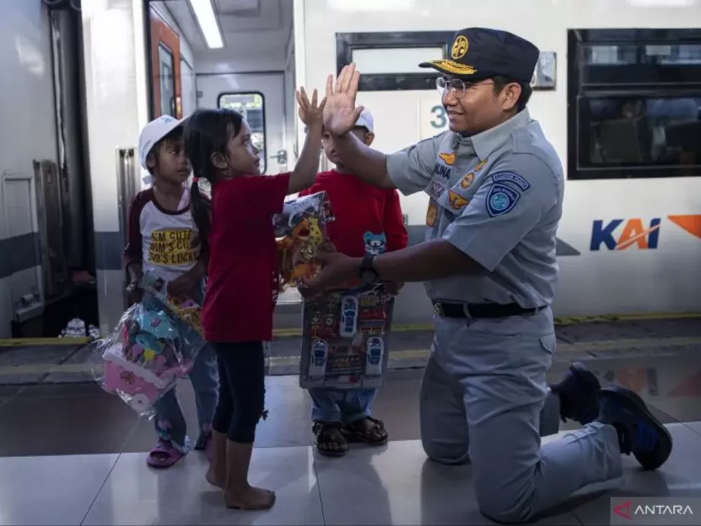 Direktur Hubungan Kelembagaan PT Jasaraharja Munadi Herlambang (kanan) memberikan mainan ke sejumlah anak peserta Mudik Gratis BUMN 2023 di Stasiun Pasar Senen, Jakarta, Minggu (16/4/2023). (ANTARA FOTO/SIGID KURNIAWAN)