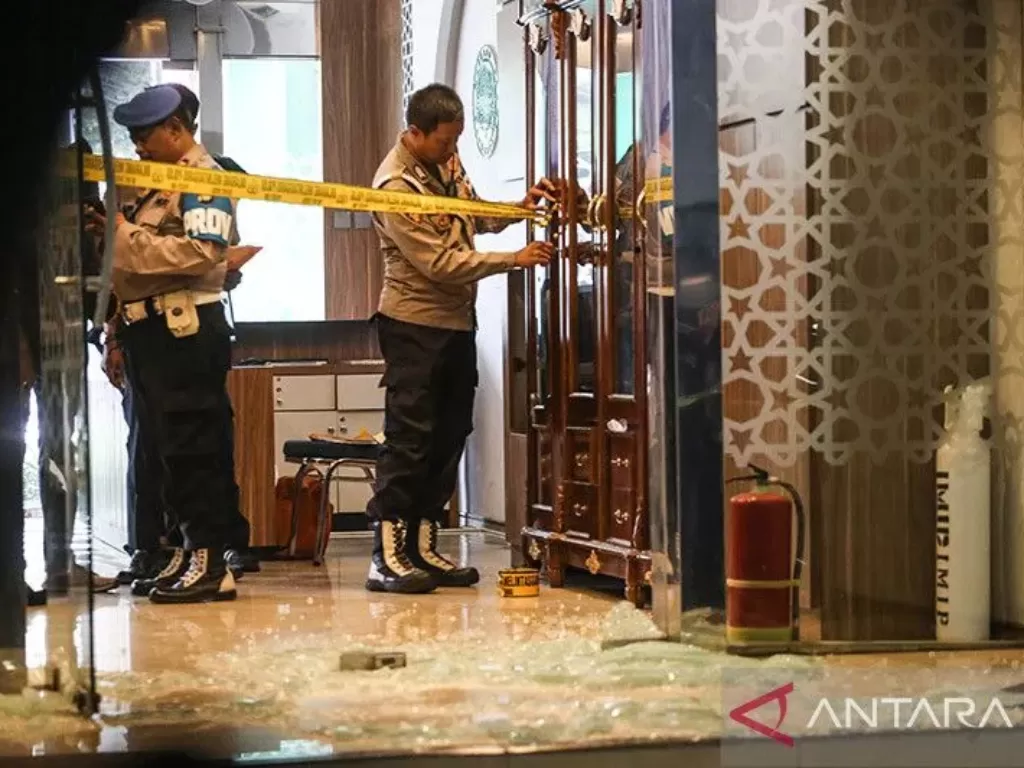 Anggota polisi memasang garis polisi di tempat kejadian perkara (TKP) dugaan penembakan di Kantor Majelis Ulama Indonesia (MUI) Pusat, Jakarta, Selasa (2/5/2023). (ANTARA FOTO/ Asprilla Dwi Adha)