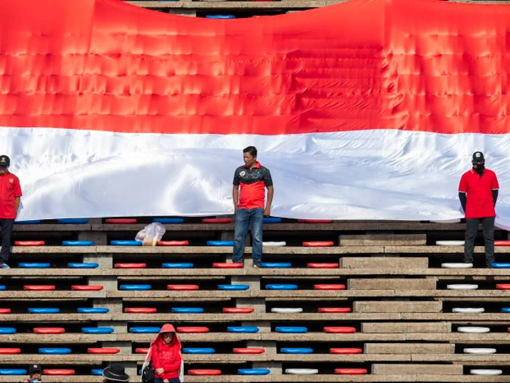 Suporter Indonesia membentangkan bendera Merah Putih raksasa saat pertandingan Grup A Sepak Bola SEA Games 2023. (ANTARA FOTO/M Agung Rajasa)