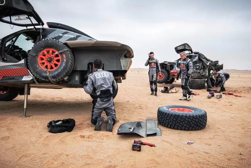Carlos Sainz -kedua dari kanan sedang membantu Mattias Ekstrom rekan setimnya di Audi Sport yang mengalami ban pecah di Etape 7 Reli Dakar 2023. (Foto: Dakar Rally)