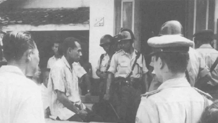 Husein bin Umar Batfari atau Oesin Batfari (kemeja putih dan diborgol) di depan pihak kepolisian. (Foto: Dokumentasi Majalah Bzzlletin) 