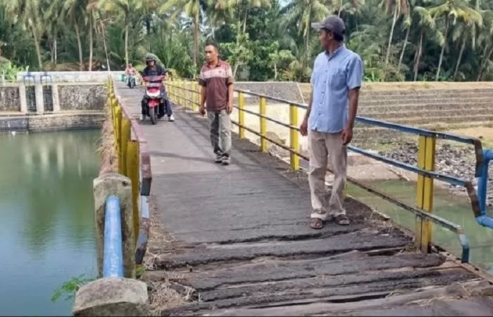 Warga berjalan kaki dan bersepeda motor melintas di Jembatan Inspeksi di atas Sungai Serang. (Foto: Asrul Sani)