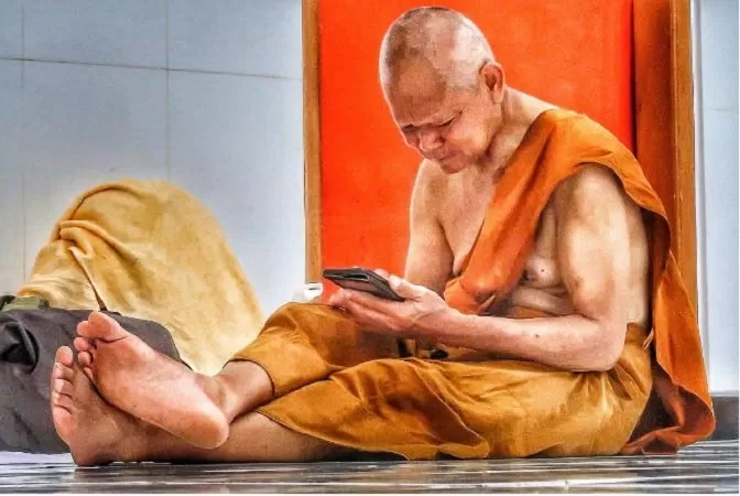 Seorang Bhikkhu yang mengikuti Thudong tengah istirahat di Vihara Adi Dharma Semarang sambil membuka Smartphone mereka untuk menggali informasi seputar perjalanan mereka ke Borobudur. (Foto: Chandra AN)