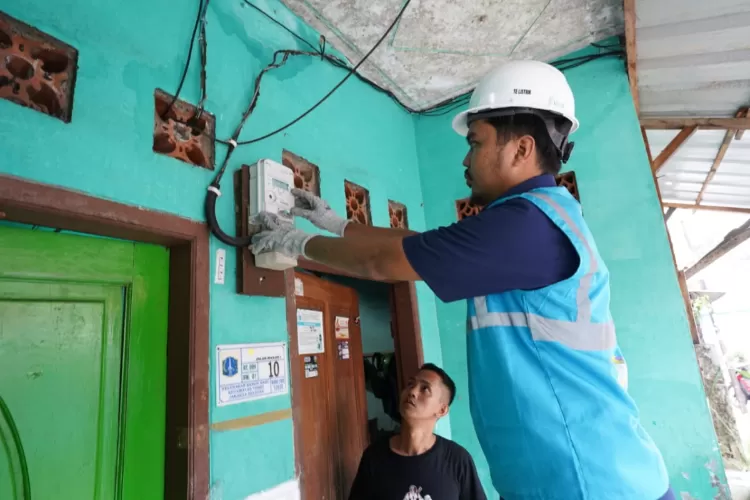 Petugas PLN sedang memasang smart meter AMI pengganti kWh lama di rumah pelanggan. Pemasangan ini dilakukan tanpa mengenakan biaya alias gratis. (DOK. PLN)