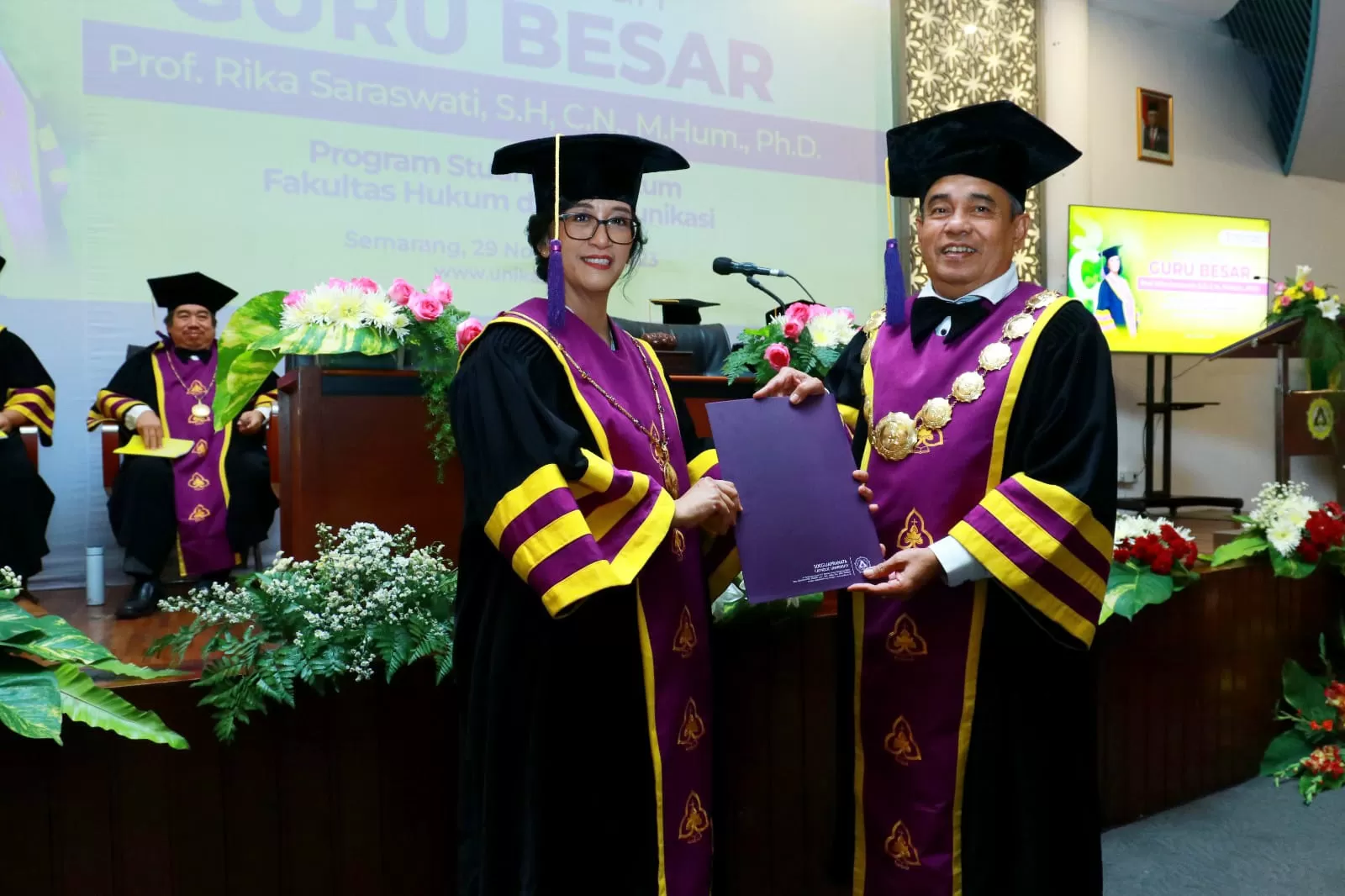 Rektor (kanan) saat menyerahkan penghargaan atas capaian guru besar kepada prof Rika.